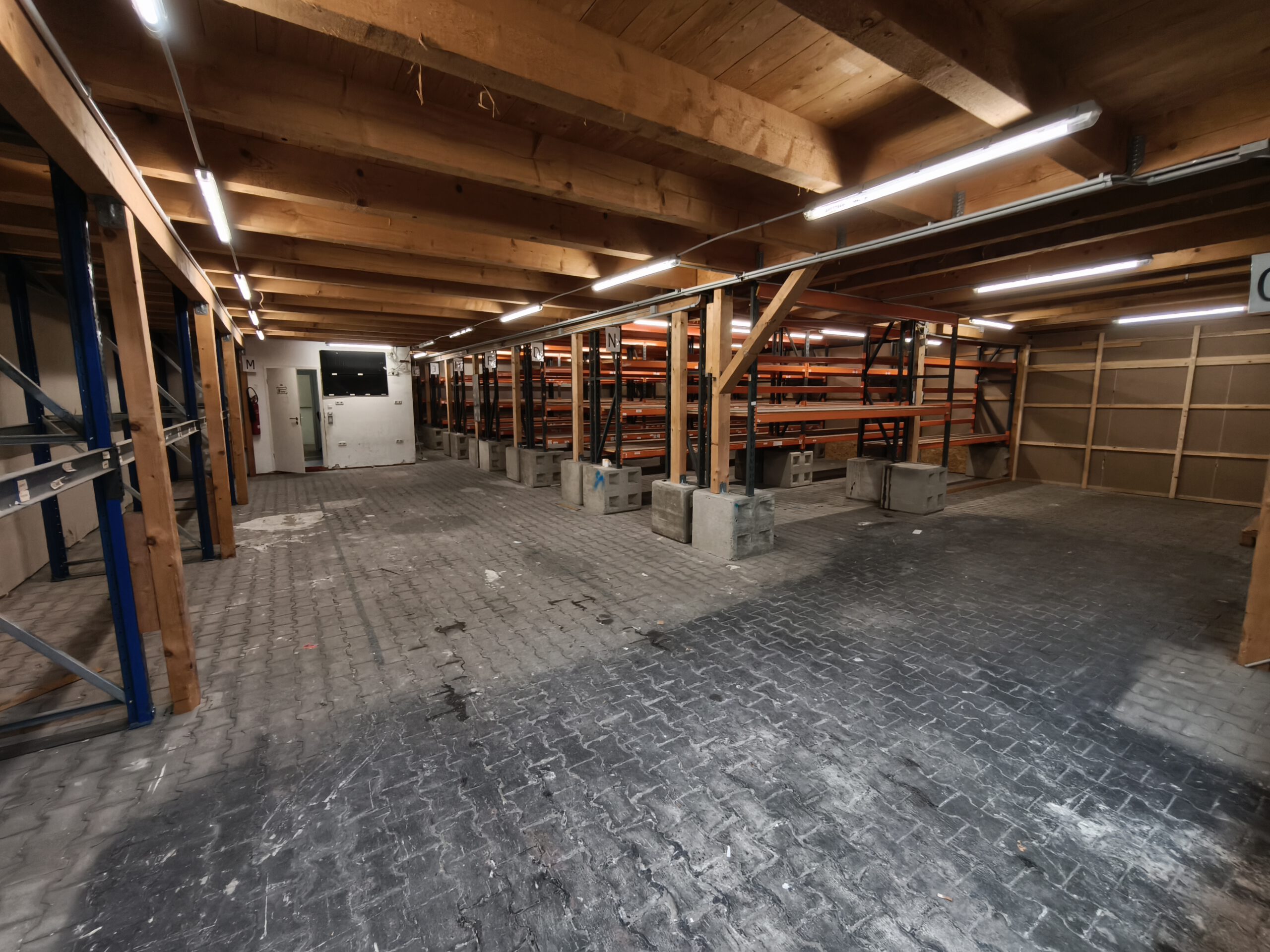 eine Versandlagerhalle mit Holzbalkendecke und Stahlregalen